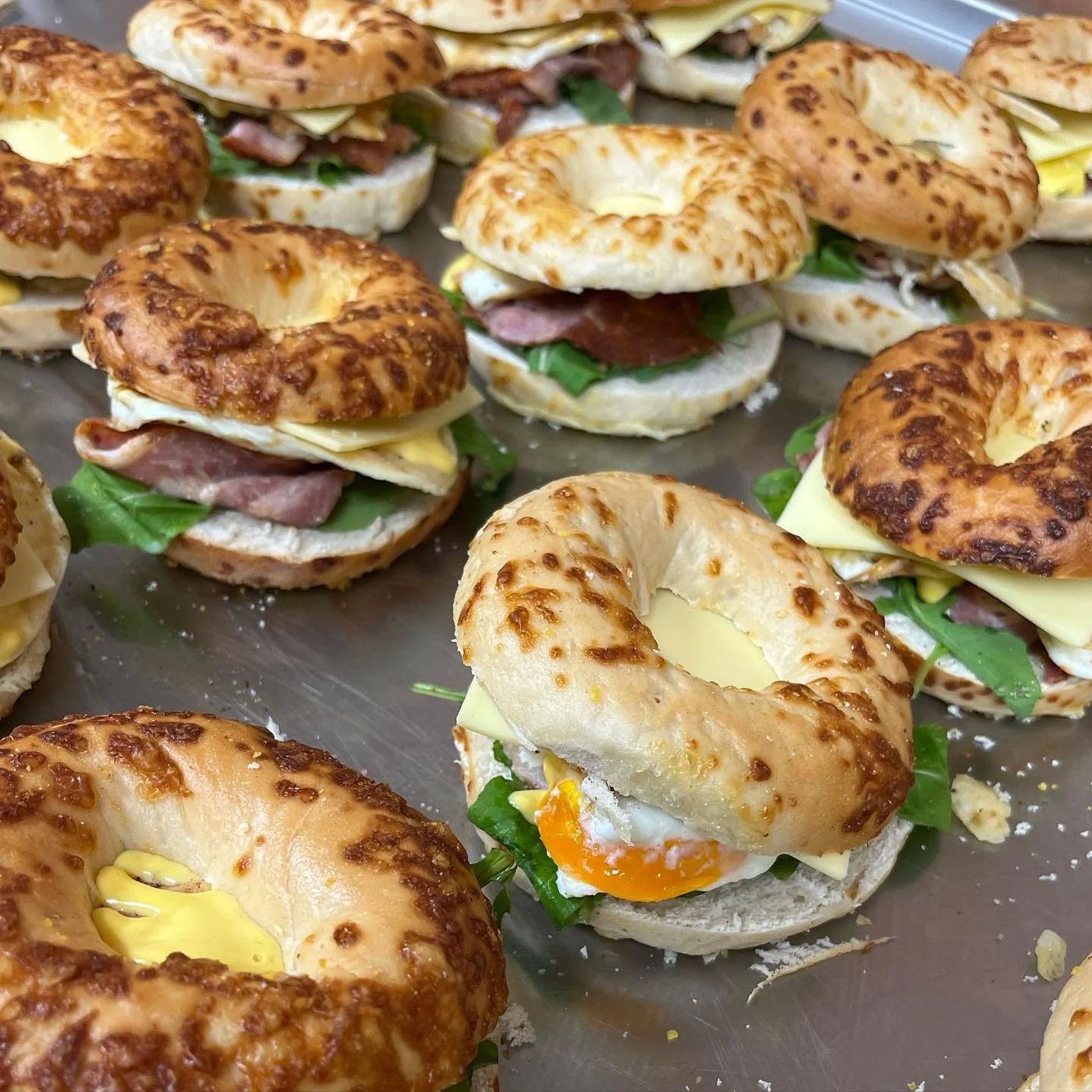 Platter of filled cheese bagels with bacon, egg and rocket ready for a catered event