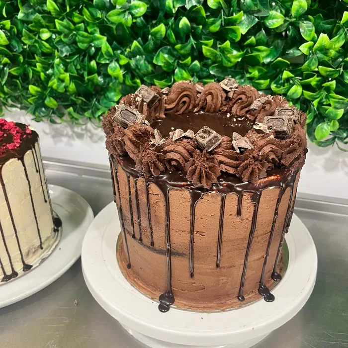 Tall chocolate drip cake with piped swirls