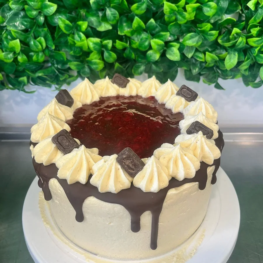 Red velvet celebration cake with piped cream swirls and a chocolate ganache centre