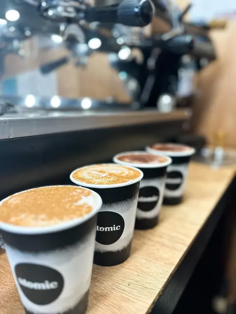 Row of dusted chai lattes lined up on the espresso machine bench