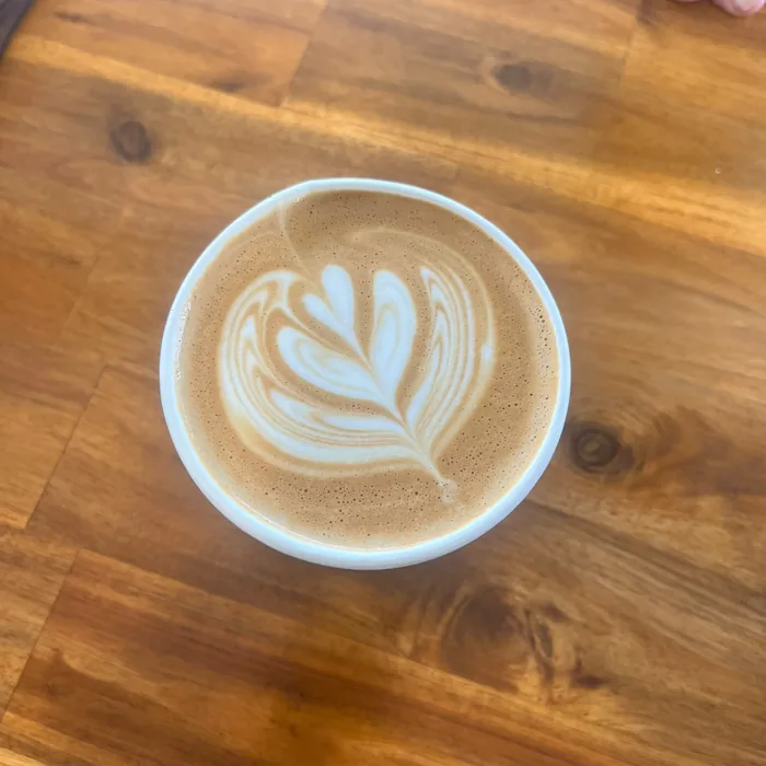 Flat white with tulip latte art on a wooden bench