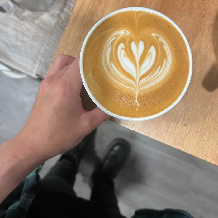 Latte held with detailed rosetta art